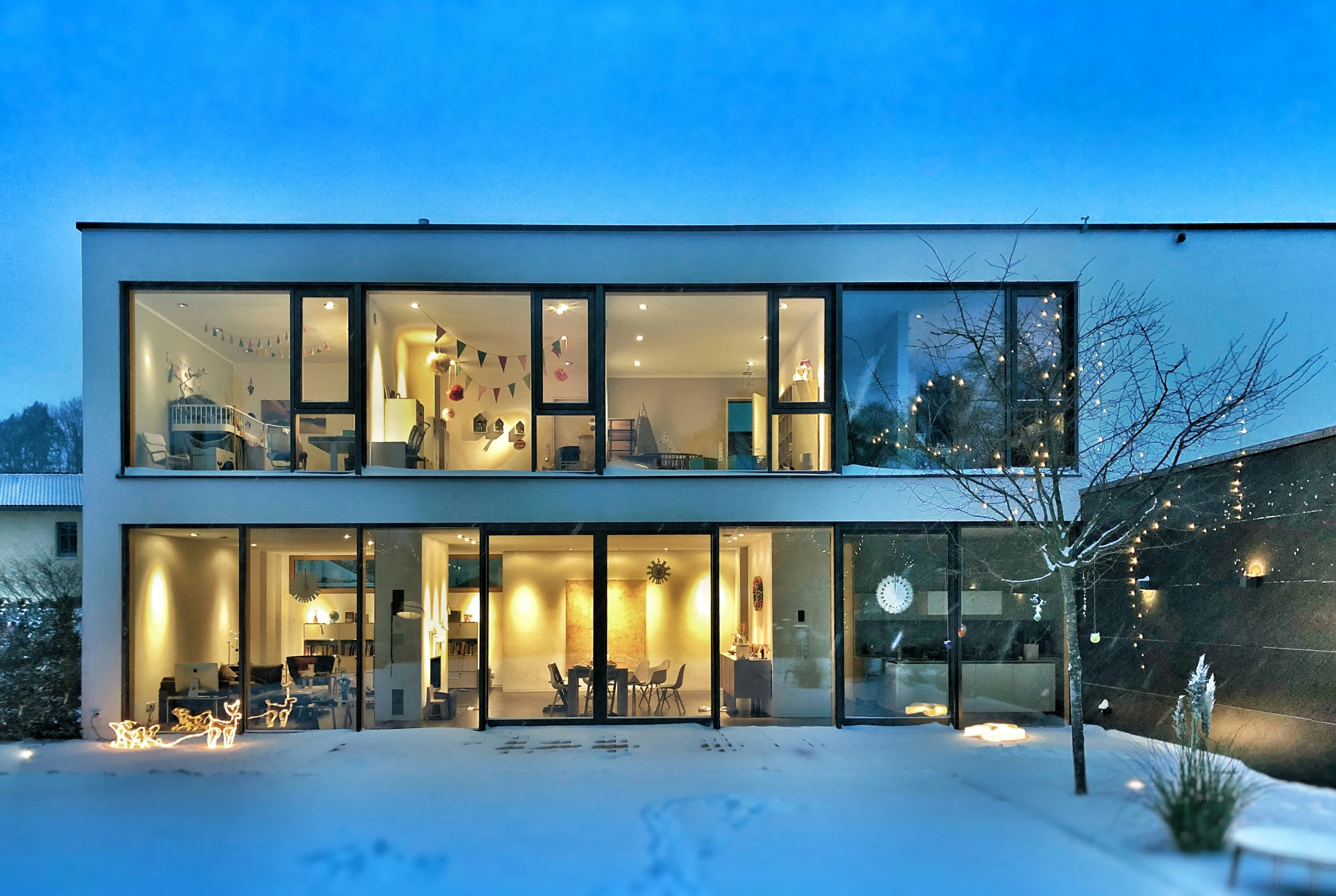 Modernes Wohngebäude mit dunkler Fassade und großen Fenstern unter blauem Himmel
